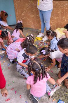Group of kids enthusiastically picking up candies from the floor in a festive setting.