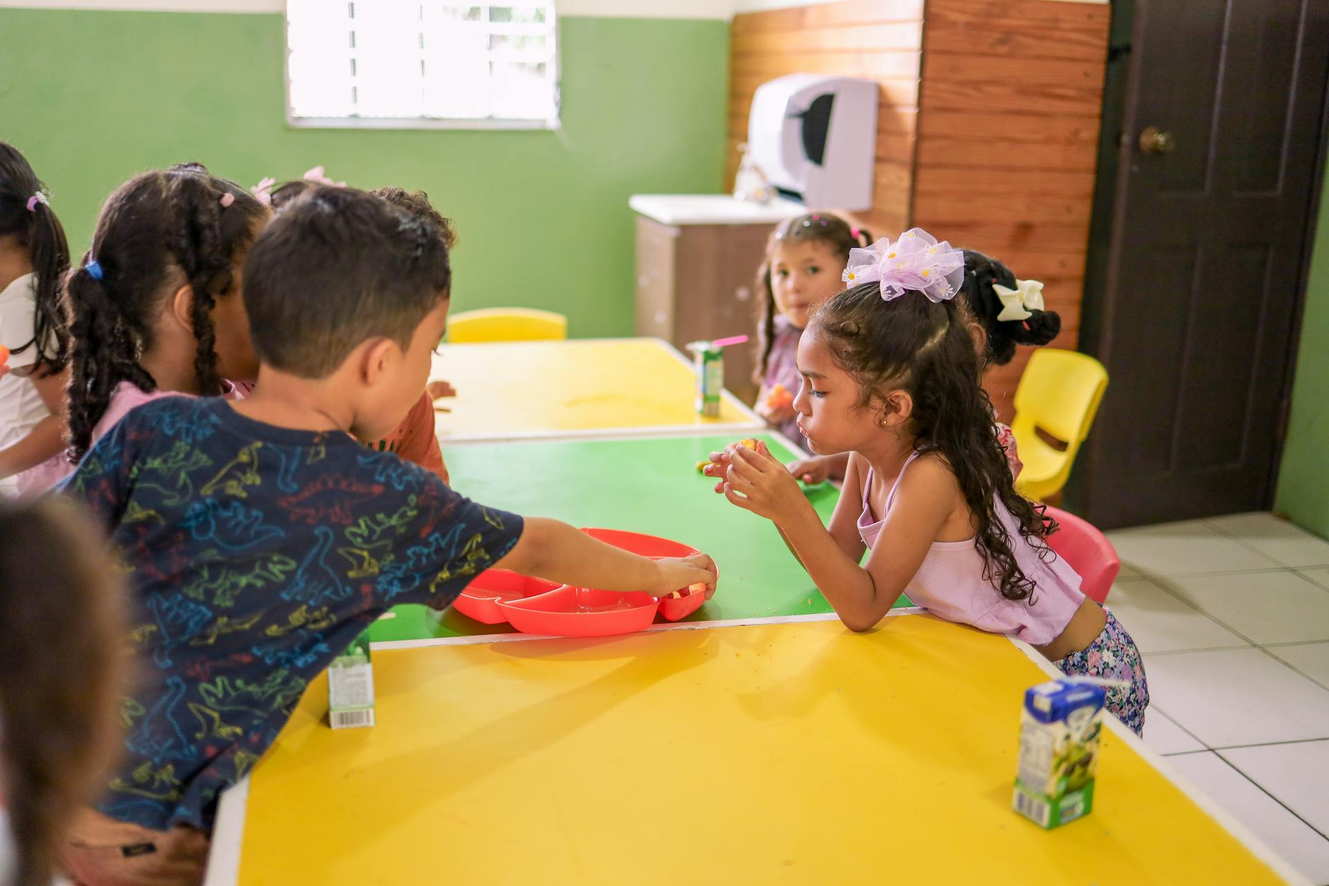 Young children enjoying a collaborative learning activity in a colorful classroom setting.