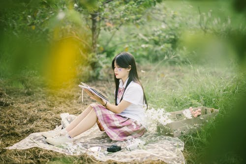 Woman Sitting at Picnic and Reading Book