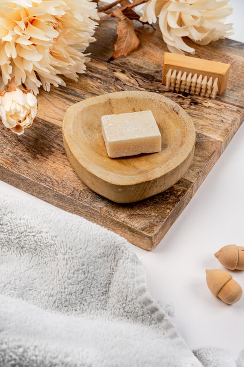 A Bar of Soap Lying in a Wooden Bowl on a Wooden Board 