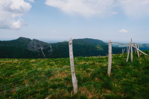 Free Rustic wooden fence overlooking lush green hills and mountains under a clear sky. Stock Photo