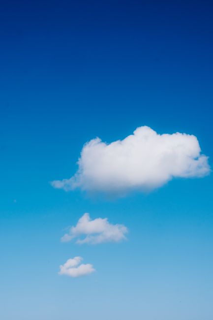 A serene blue sky with fluffy white cumulus clouds floating peacefully.