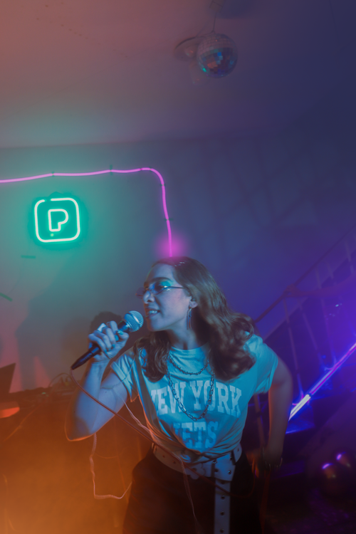 Free A vibrant nightclub scene in CDMX featuring a woman energetically singing with a microphone. Stock Photo