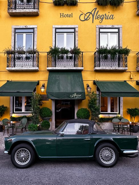 Classic car in front of Hotel Alegria's vibrant facade in Lisbon, Portugal.