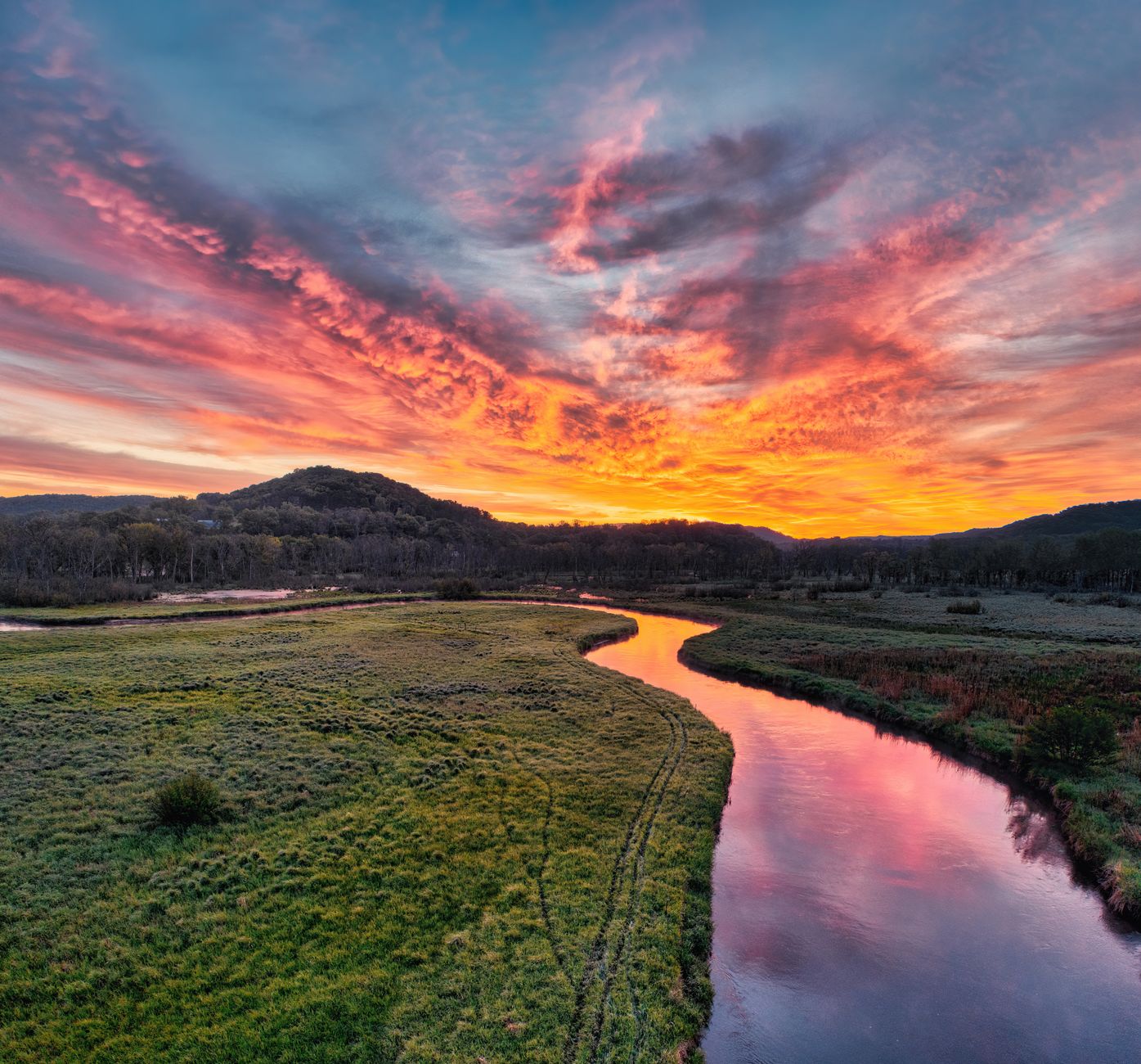 Stunning sunset reflecting in a winding river surrounded by lush meadows and hills in Tell, WI.