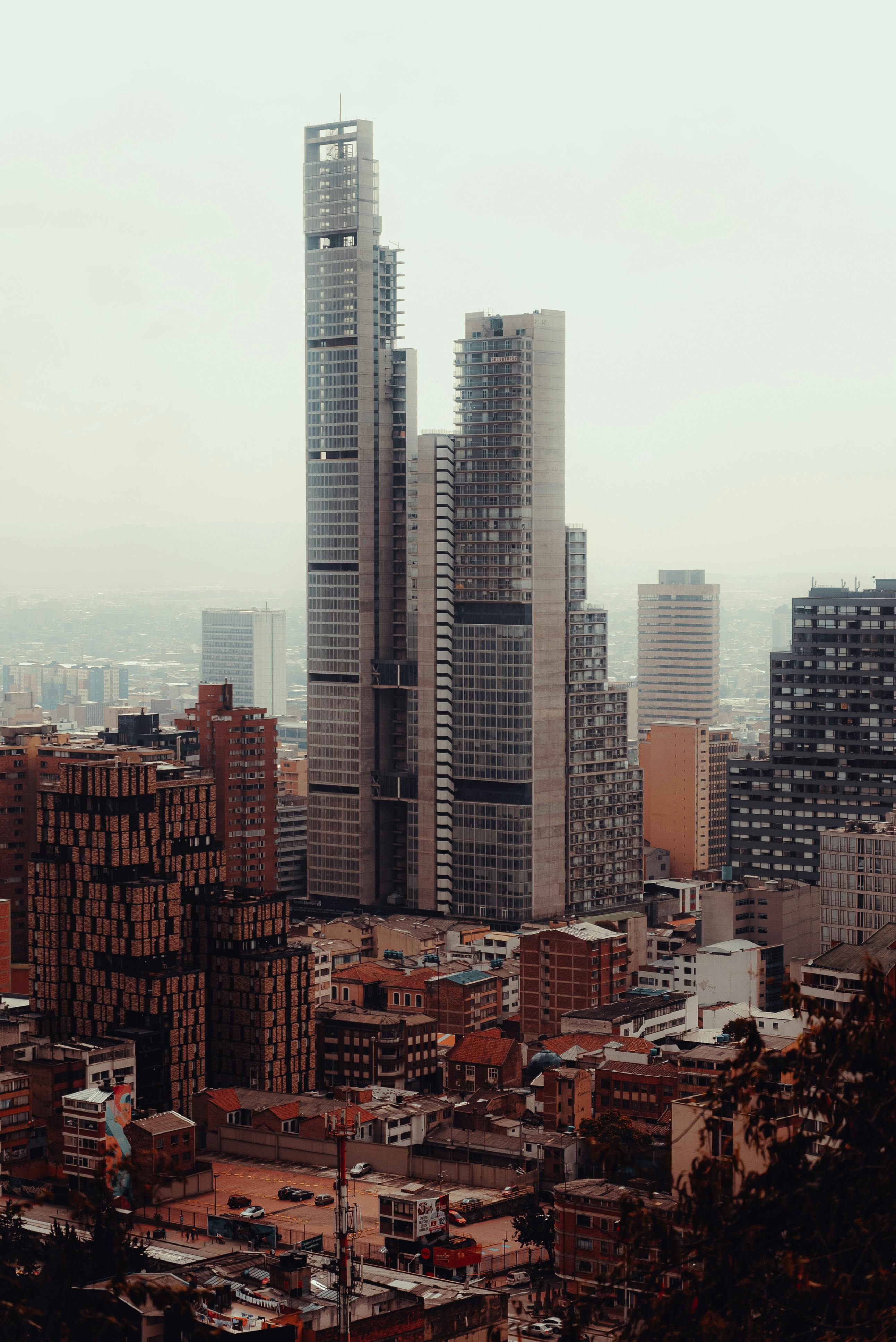 A high-rise cityscape of Bogotá, showcasing modern skyscrapers under a hazy sky.
