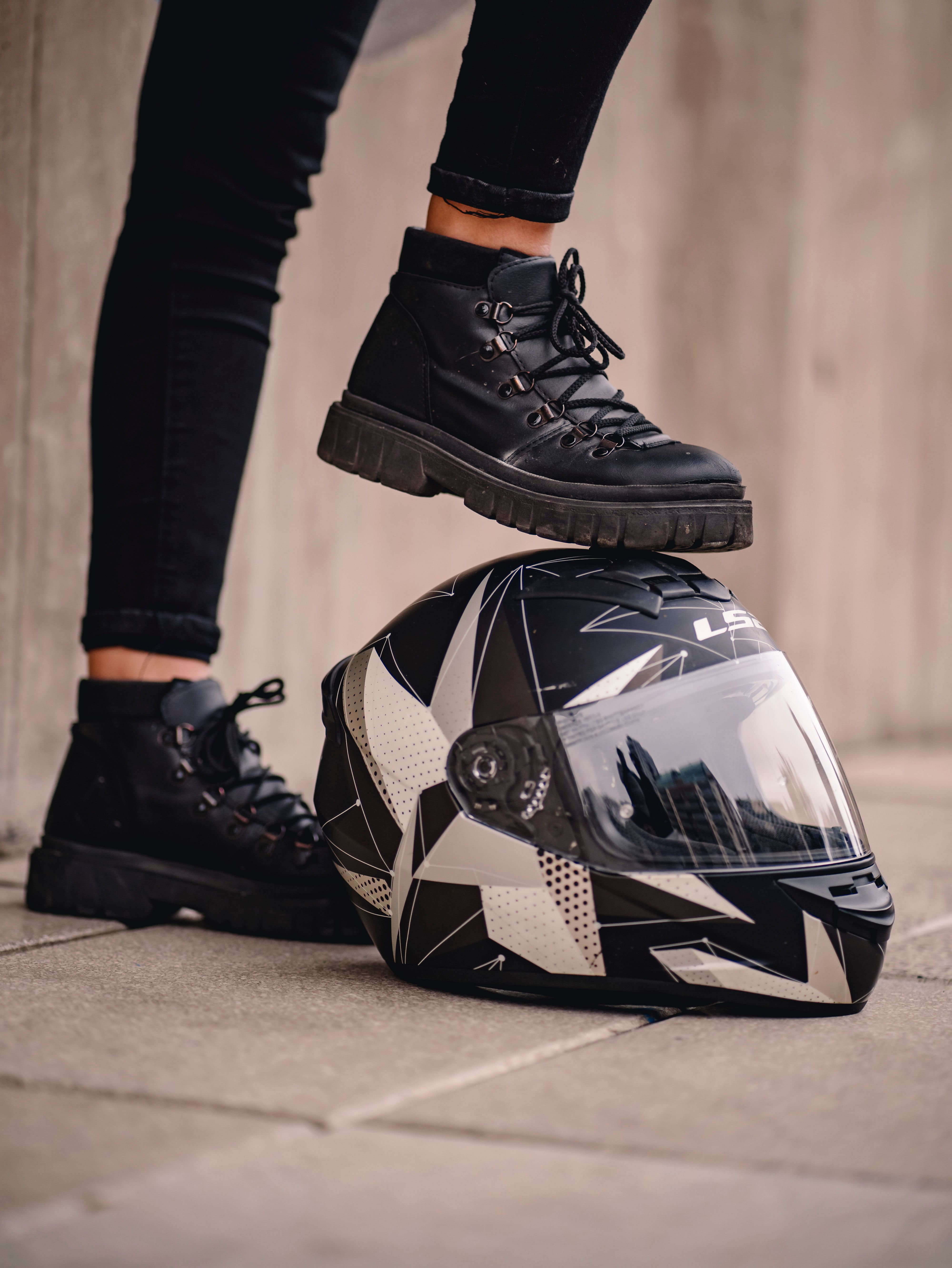 A person standing on a sidewalk with their feet on a motorcycle · Free ...