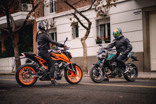 Free Two riders on motorbikes engage in conversation on an urban street, highlighting street style. Stock Photo