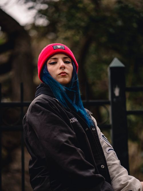 Free Portrait of a woman in a red beanie and jacket, showcasing modern street fashion. Stock Photo
