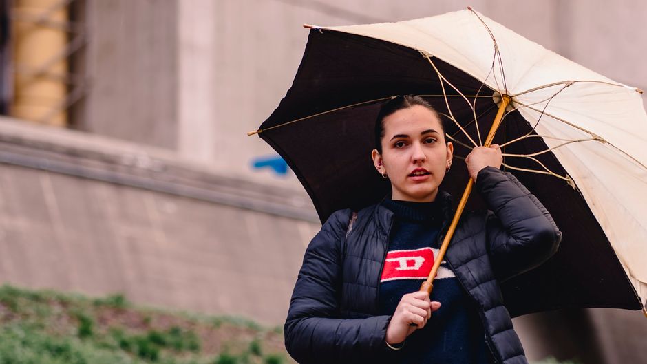 Fashionable woman holding an umbrella in an urban setting, showcasing contemporary style and expression.