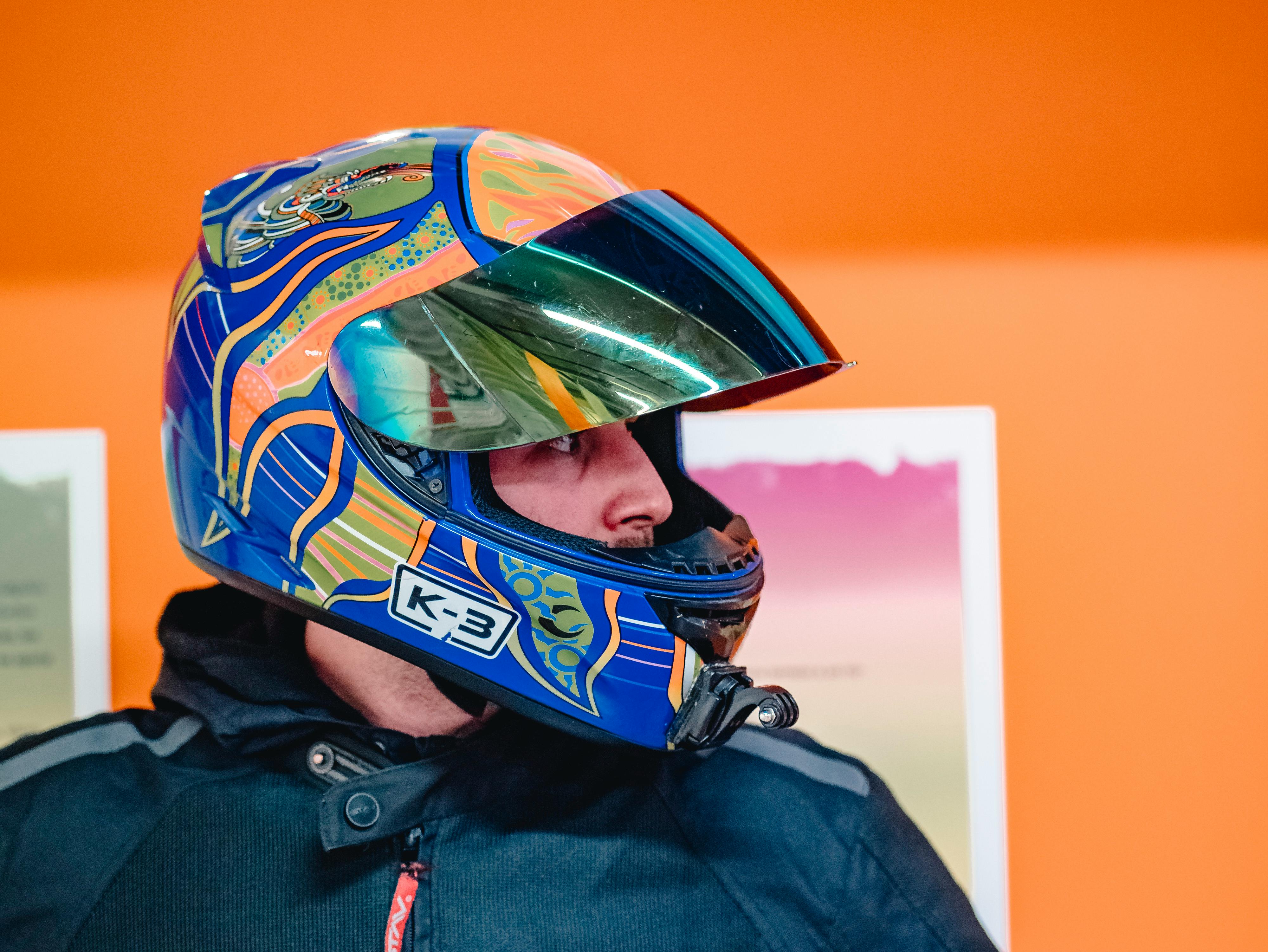 Vibrant motorbike helmet portrait against an orange background, showcasing modern design and safety gear.