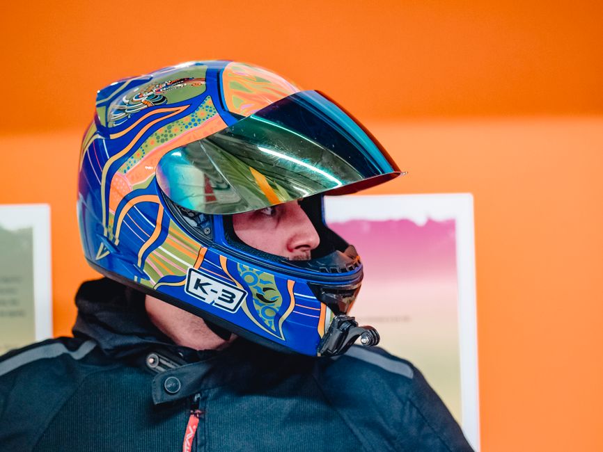 Vibrant motorbike helmet portrait against an orange background, showcasing modern design and safety gear.