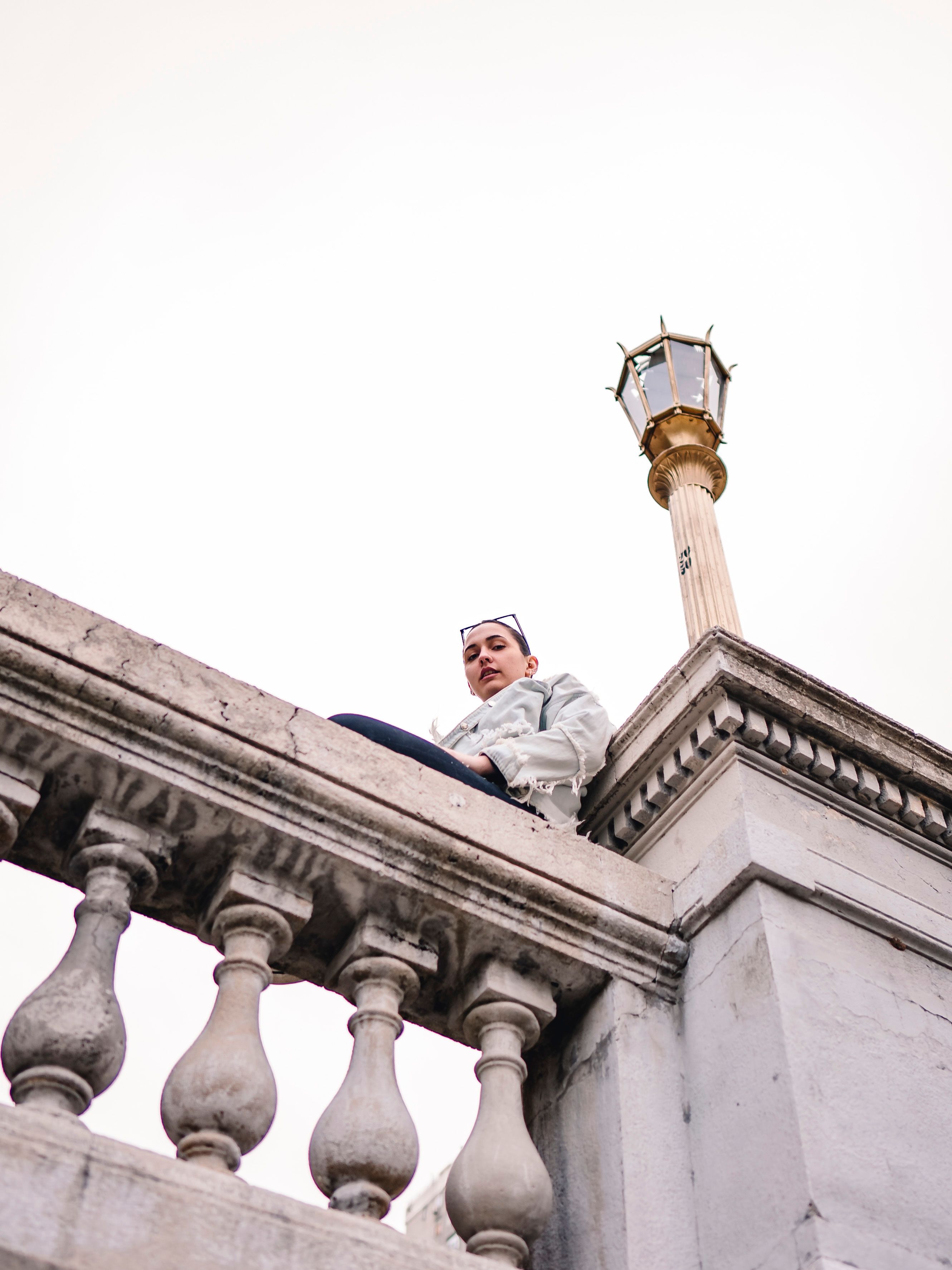 A woman sitting on the railing of a bridge · Free Stock Photo