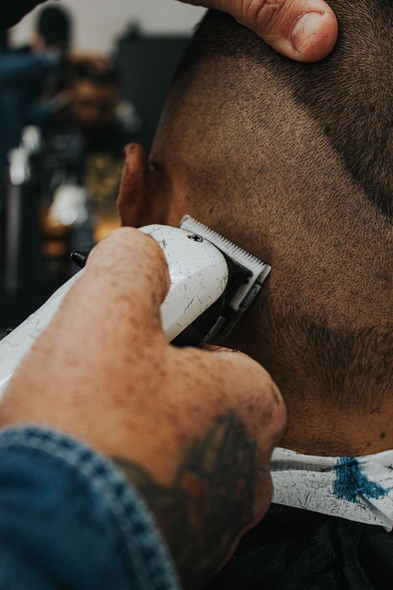 Close-up of clippers cleaning up the side of a client's fade