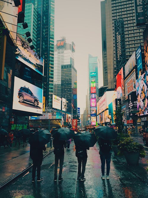 бесплатная Четыре человека под зонтиком, стоя возле зданий Стоковое фото