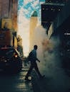 黄昏时分，一名男子走过被蒸汽笼罩的城市街道