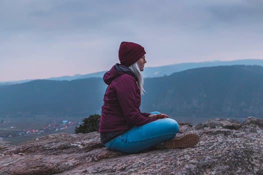 女人坐在岩石上，欣赏着宁静的山景