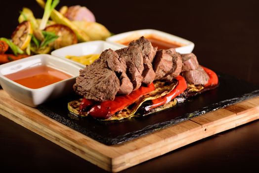 A delicious gourmet steak with grilled vegetables and various sauces. Perfectly styled for food photography.