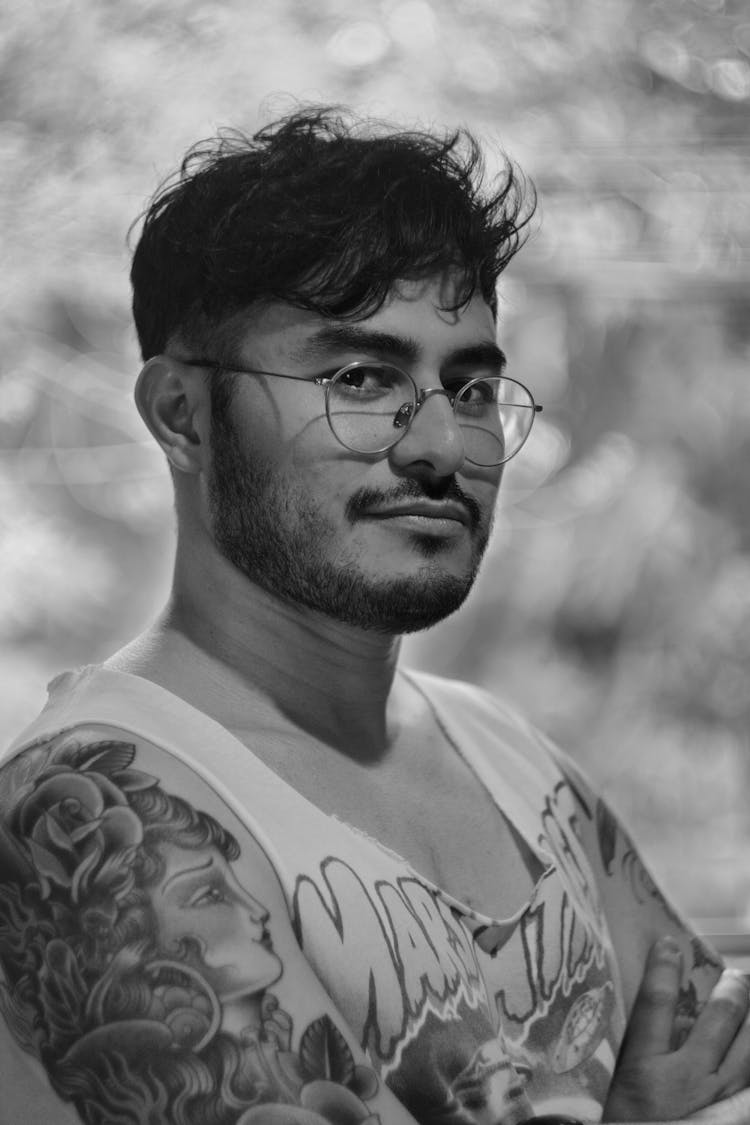 Portrait Of A Young Man In Glasses With Tattoos On His Arm In Black And White