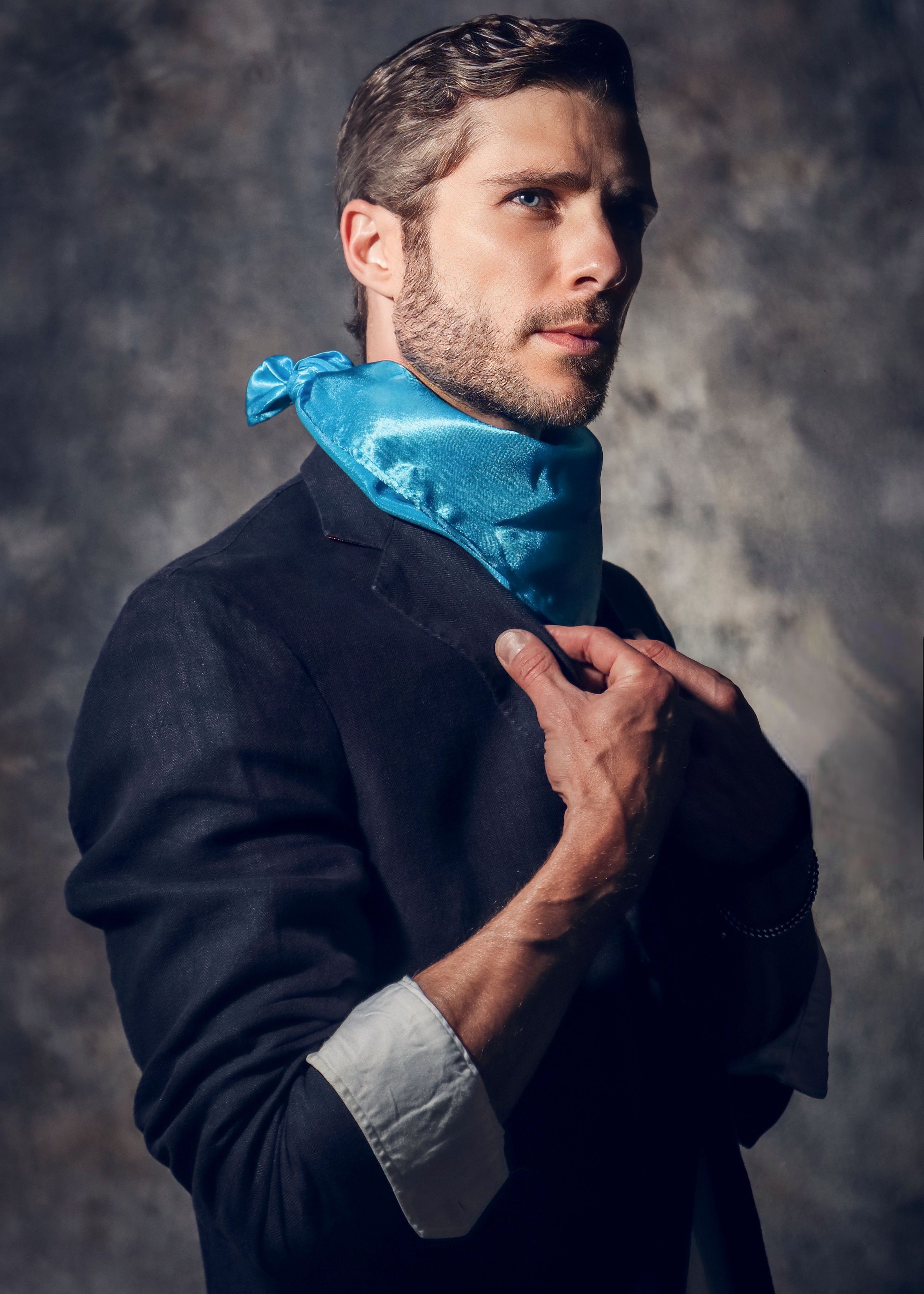 A sophisticated portrait of a fashionable man with a blue scarf, exuding elegance and style.