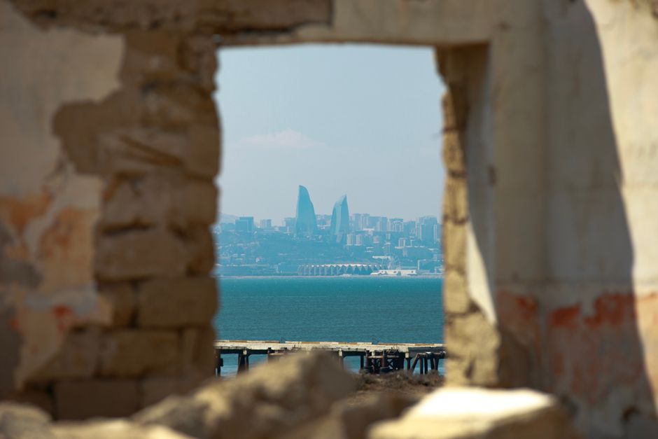 Framed view of Baku's skyline through ancient ruins, capturing modern architecture.