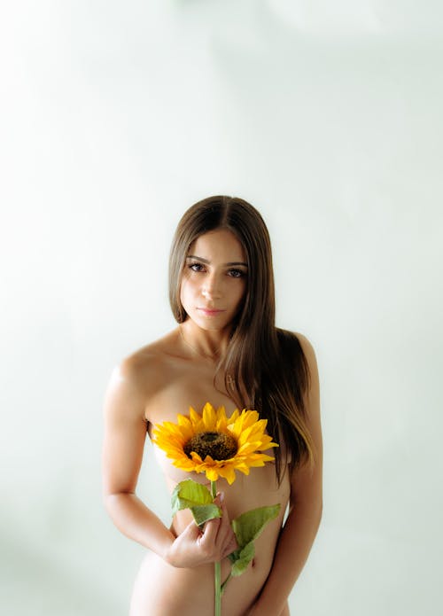 Naked Young Woman Holding a Sunflower