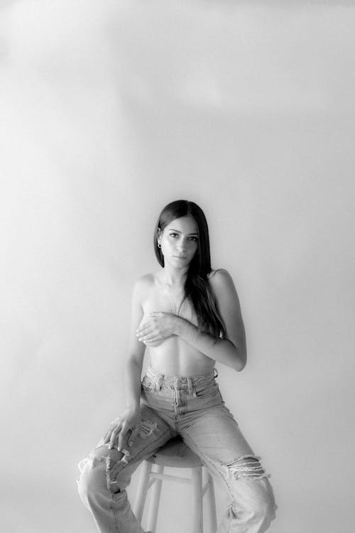 Model Wearing only Distress Jeans Sitting on a Stool