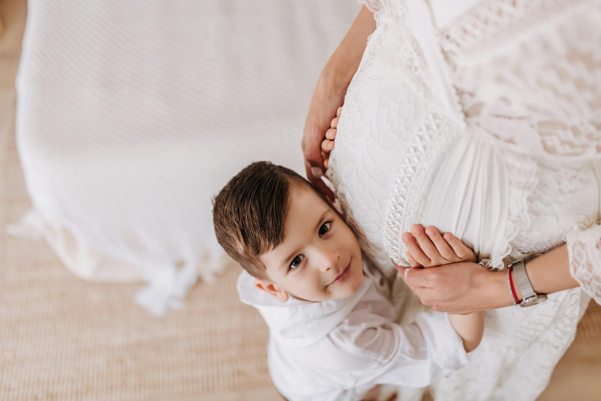 A Little Boy Standing next to His Pregnant Mother