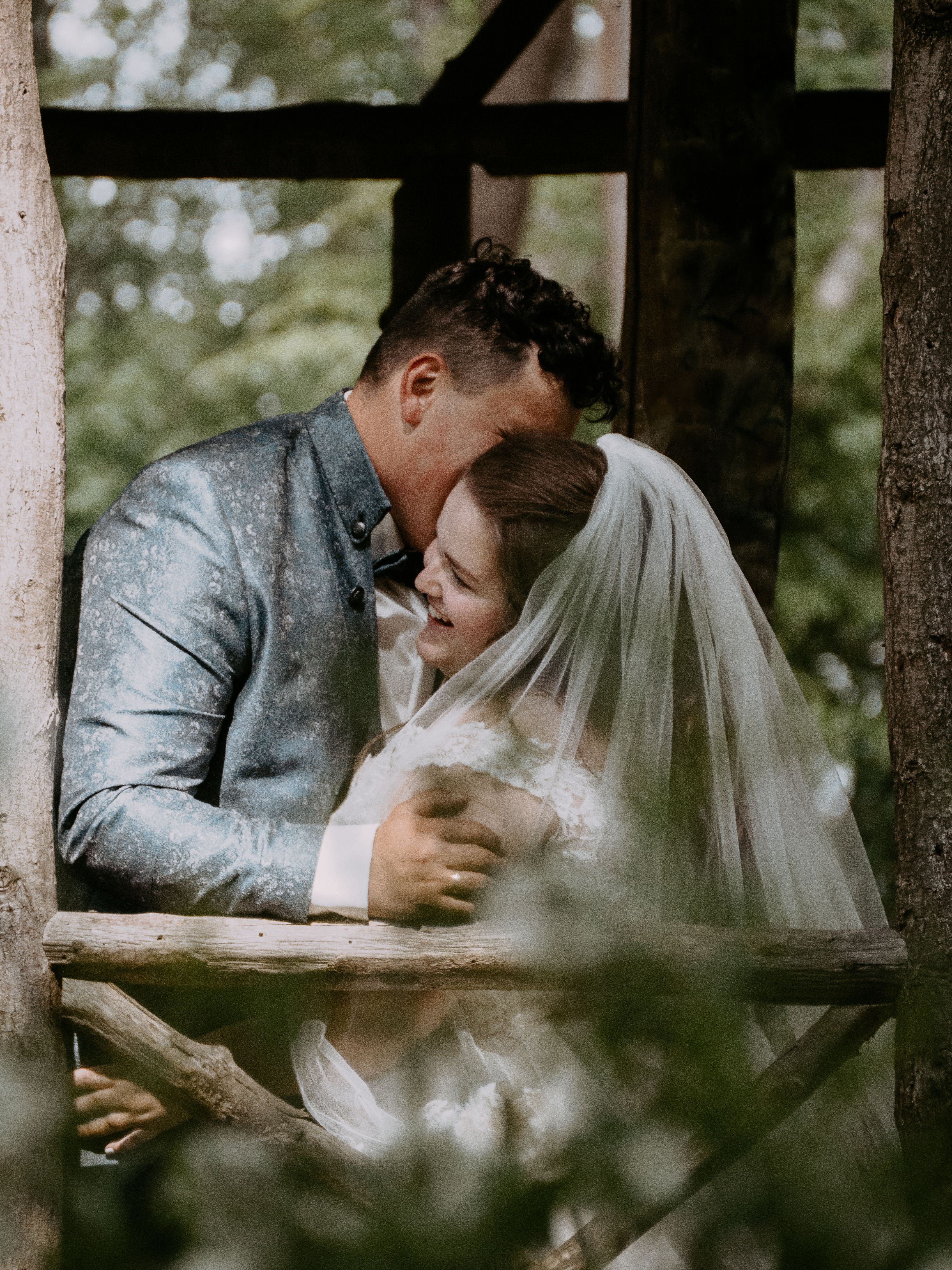 A newlywed couple embraces lovingly in a serene outdoor setting.
