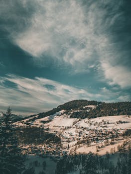 冬季的雪山村庄在壮观的天空下，展现出一幅风景如画的景观