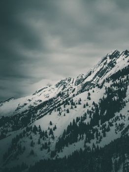 Dramatic snow-covered mountain landscape in winter with a moody sky.