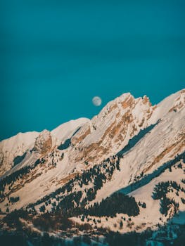 在晴朗的天空下，可以看见月亮，还能拍到雪山