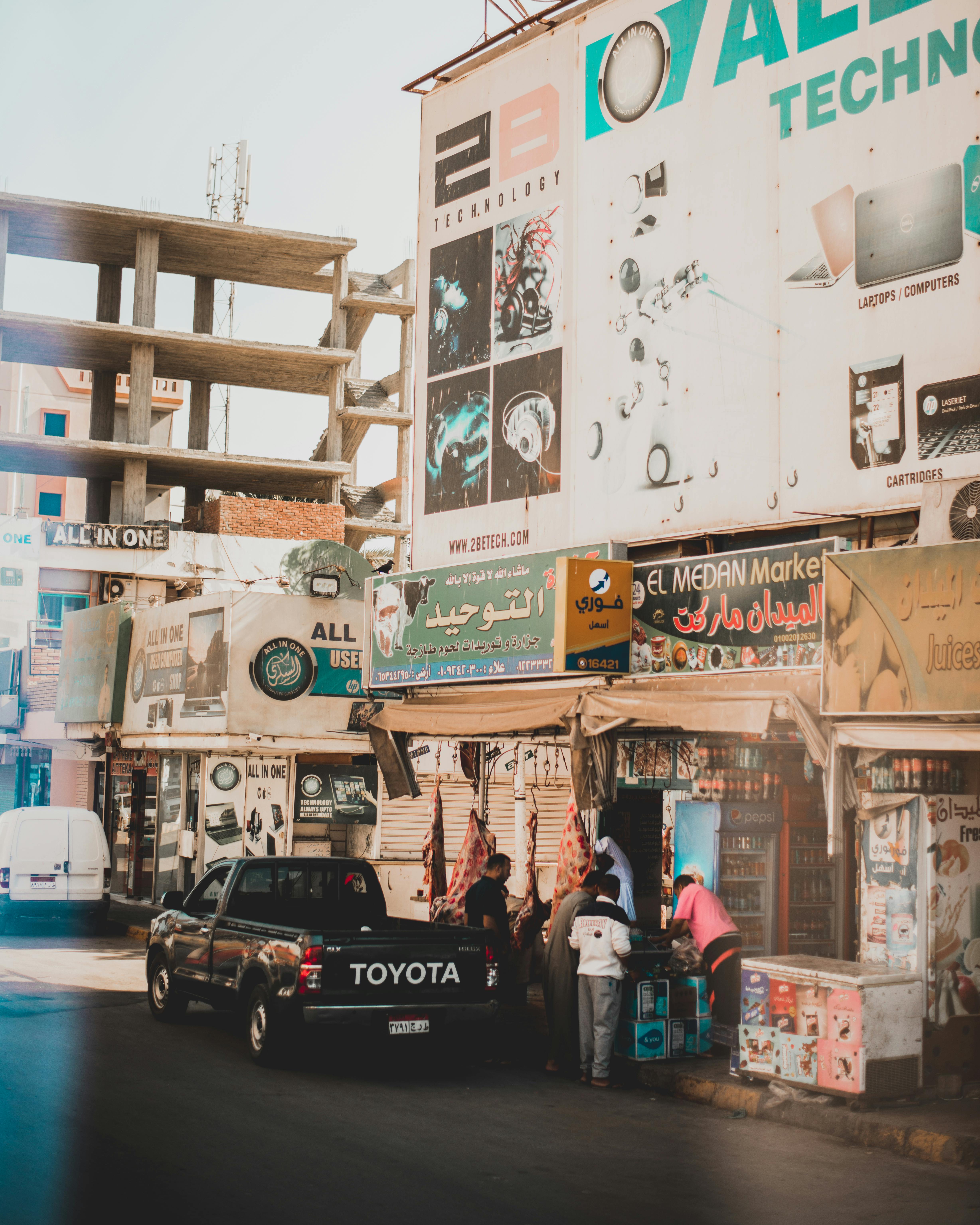 热闹的城市街景中，人们购物、车辆穿行，还有充满活力的标志