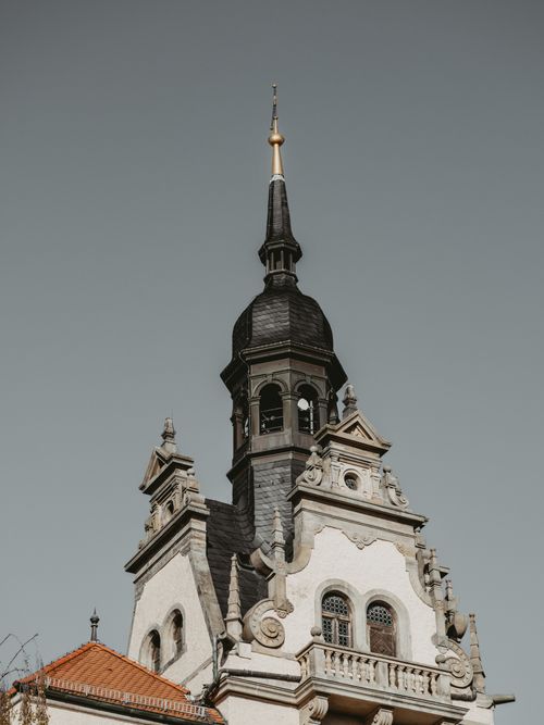 Free A low angle view of a historic church spire showcasing intricate architectural details against a clear sky. Stock Photo