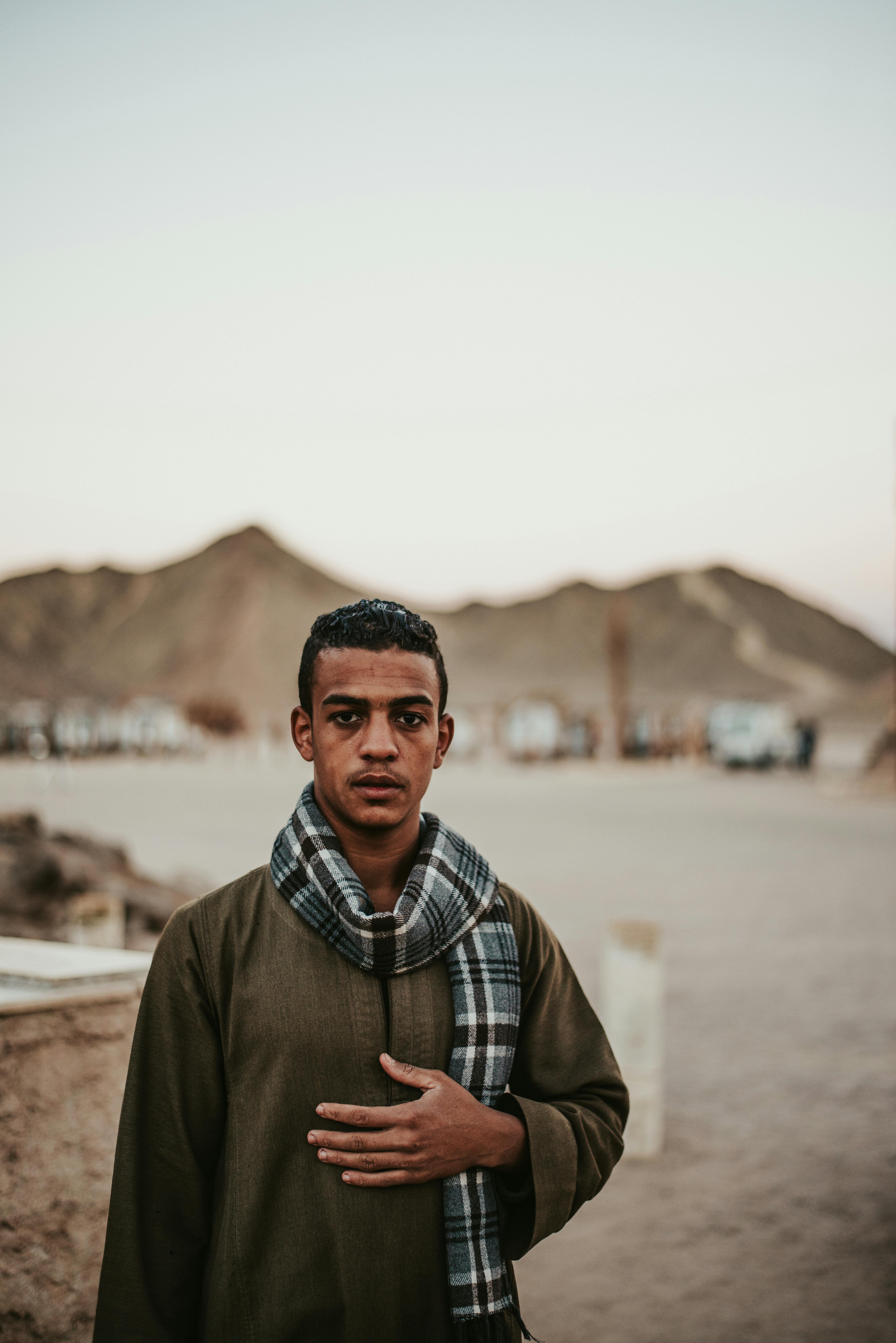 沙漠风景中，一名身着传统服装、头戴格子围巾的年轻人肖像
