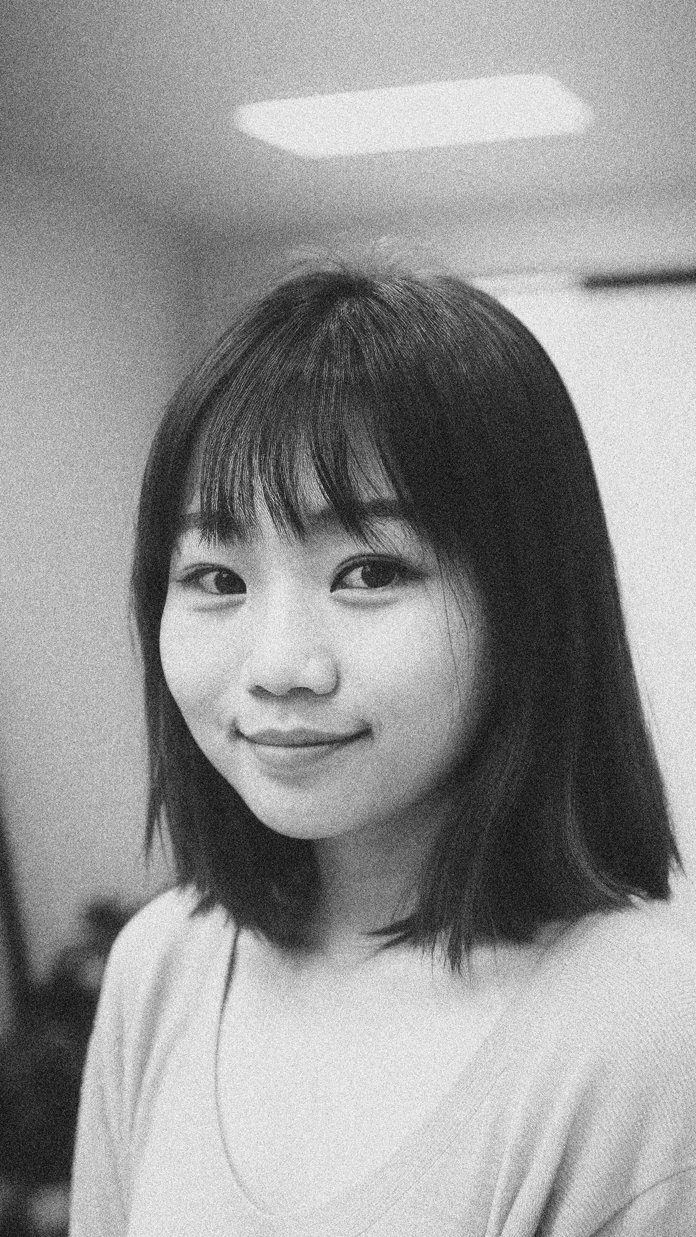 Charming black and white portrait of a young woman with long hair, smiling indoors.