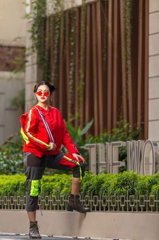 Stylish woman in vibrant red jacket posing in an urban environment in Dhaka, Bangladesh.