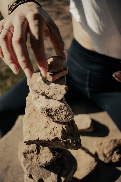 Woman Hand Putting Stones on Sunlit Heap