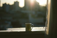窗台上放着一个马克杯，背景是城市天际线和日出