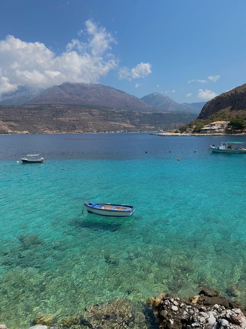 Free A tranquil view of boats on the clear waters of Limeni, Greece, under a bright sky. Stock Photo