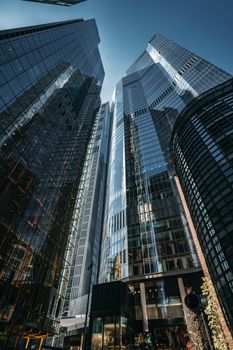 Dramatic view of tall glass skyscrapers in London's financial district on a sunny day.