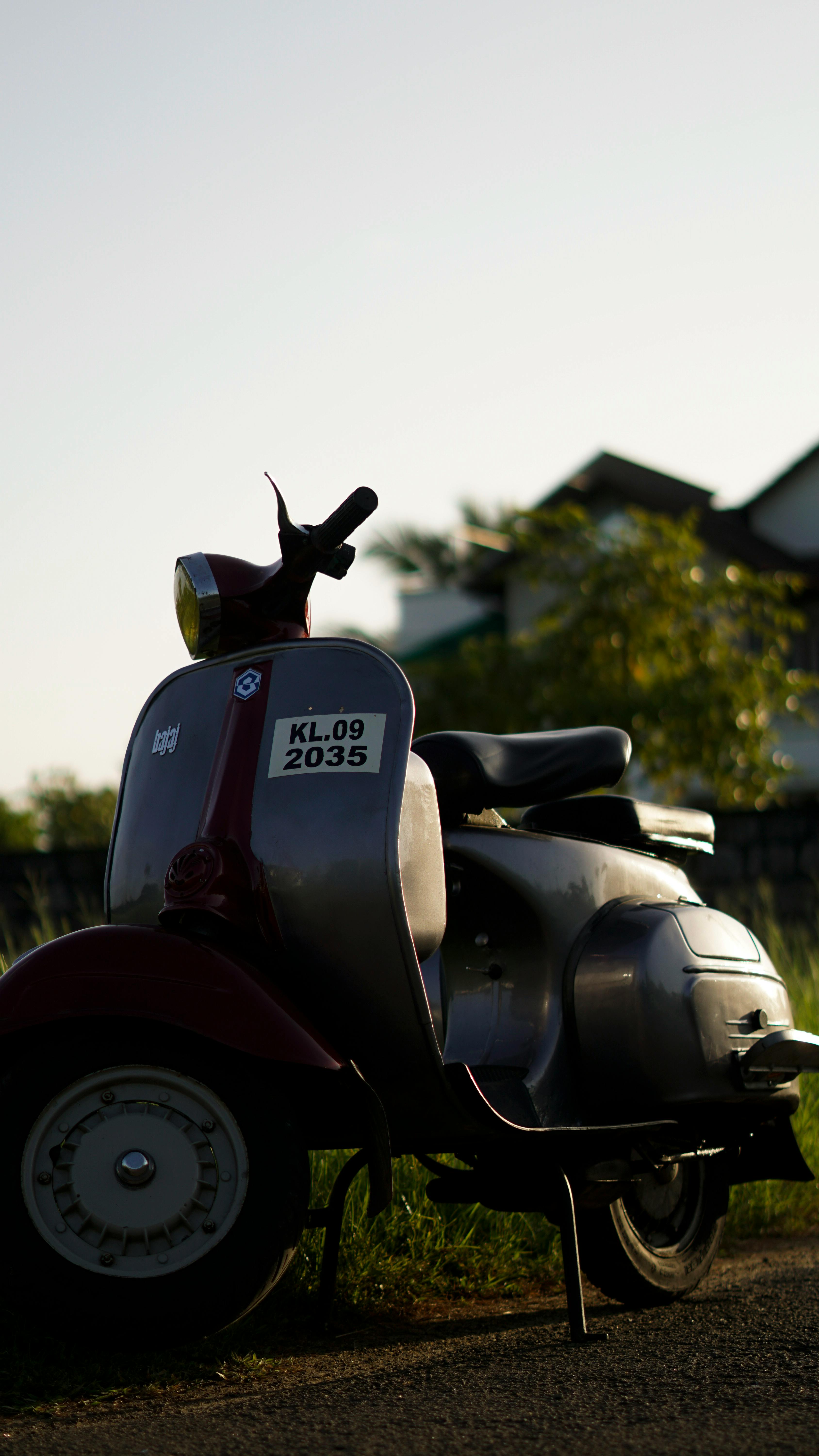 A classic vintage scooter parked on a scenic country road during sunset.