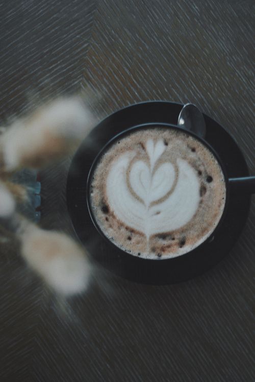 Free Top view of a creamy cappuccino with heart latte art in a black cup, perfect for coffee lovers. Stock Photo