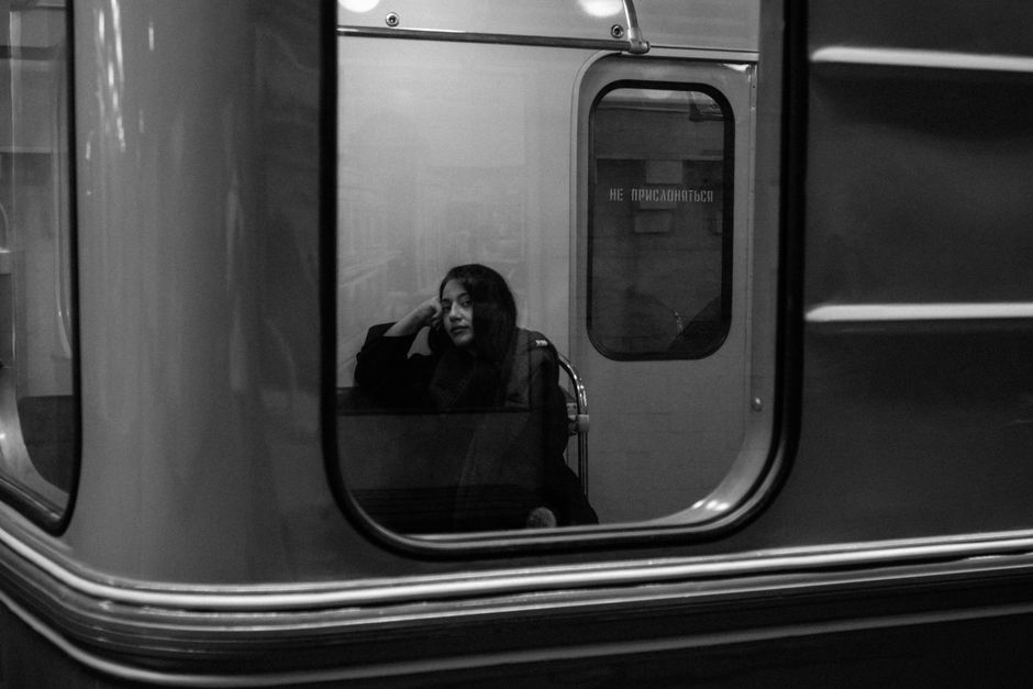 A young woman sits thoughtfully on a subway train in Baku, Azerbaijan, captured in black and white.