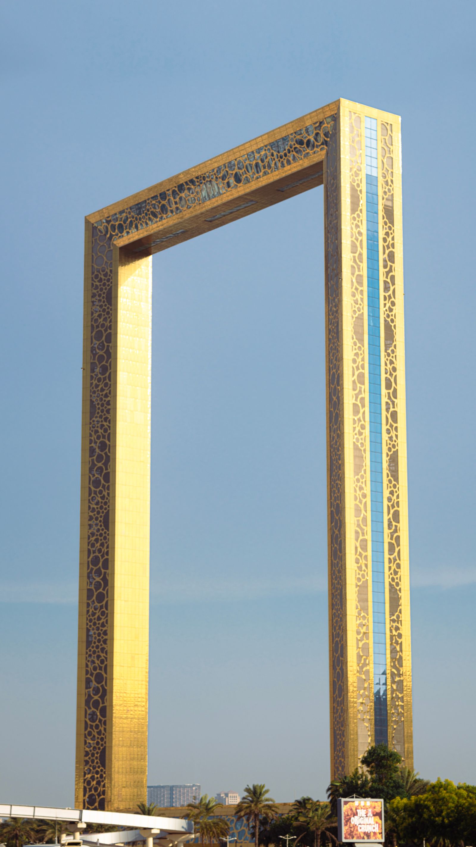 Dubai Frame - golden monumental arch against a clear blue sky with palm trees