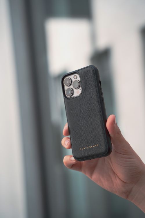 Free Close-up of a luxury smartphone in a black leather case held by a hand indoors. Stock Photo