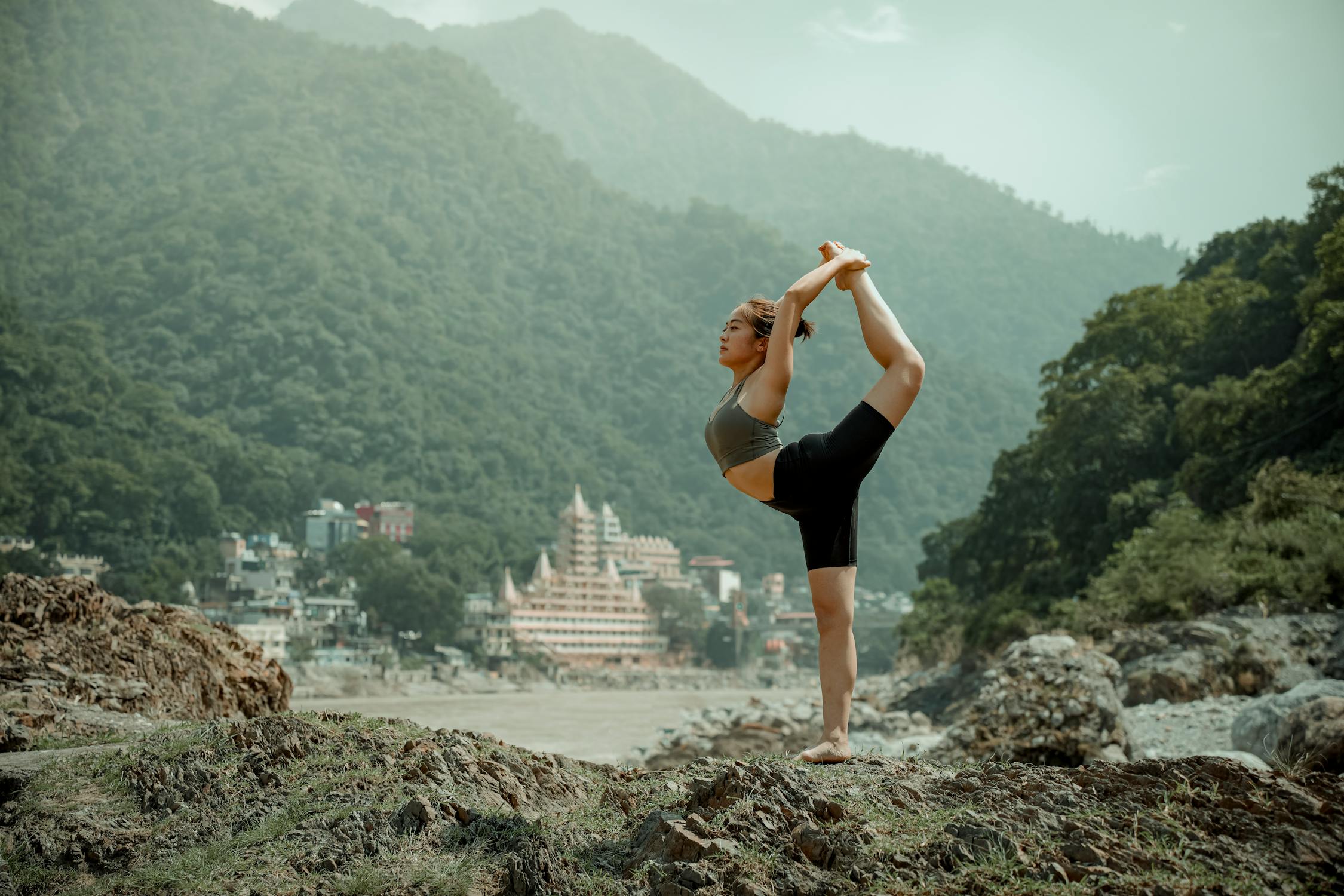 free photo of young woman standing on one leg on mountain in rishikesh india