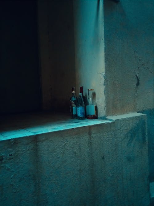 Four Empty Bottles Standing by a Wall