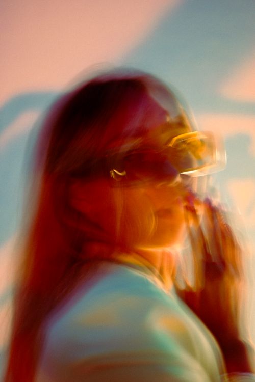 Free Blurry and artistic long-exposure portrait of a woman wearing sunglasses, creating a dreamy look. Stock Photo