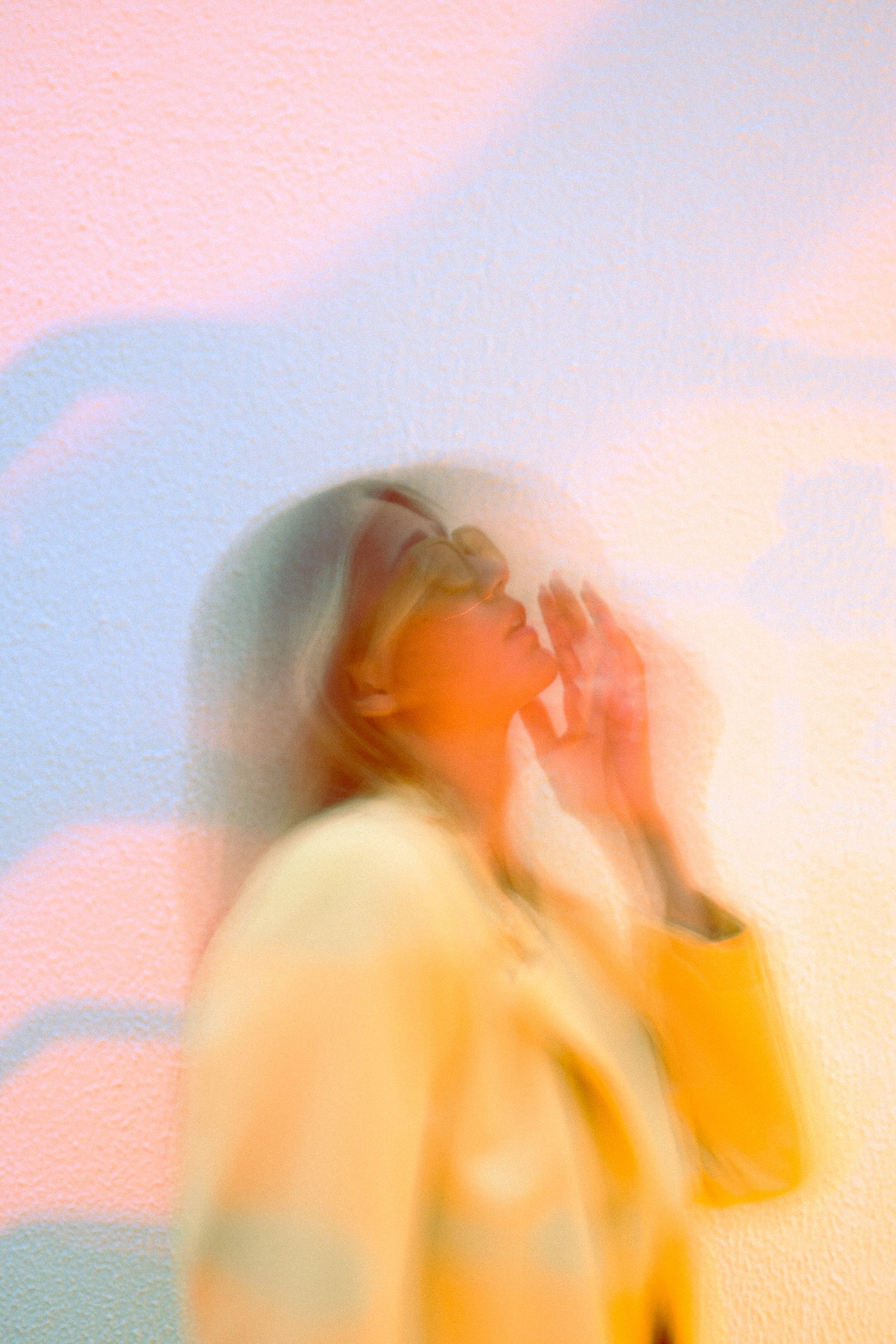 Creative blurred portrait of a woman in a yellow blazer captured in motion, exuding a soft and artistic vibe.